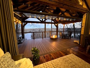 Um deck de madeira com lareira, área de estar ao ar livre e vista para uma paisagem nevada.