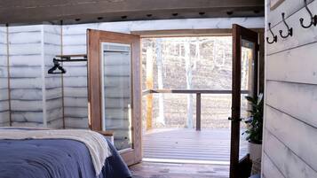 A bedroom with a bed, a wooden ceiling, a window, and a balcony.