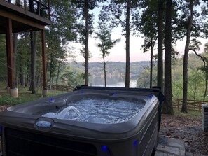 Uma banheira de hidromassagem ao ar livre com vista para árvores e uma paisagem distante.