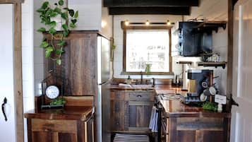 Une cuisine compacte avec des meubles en bois, une cuisinière encastrée, un évier et une fenêtre donnant sur un beau paysage.
