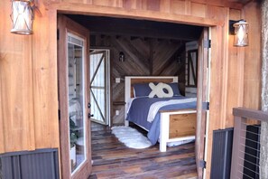 Een houten slaapkamer met een bed, een raam en een deur.