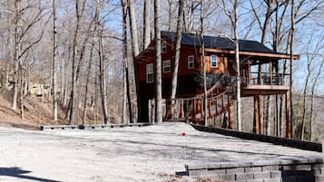Une cabane avec une façade en bois, un balcon et un escalier menant à une plateforme d’observation.