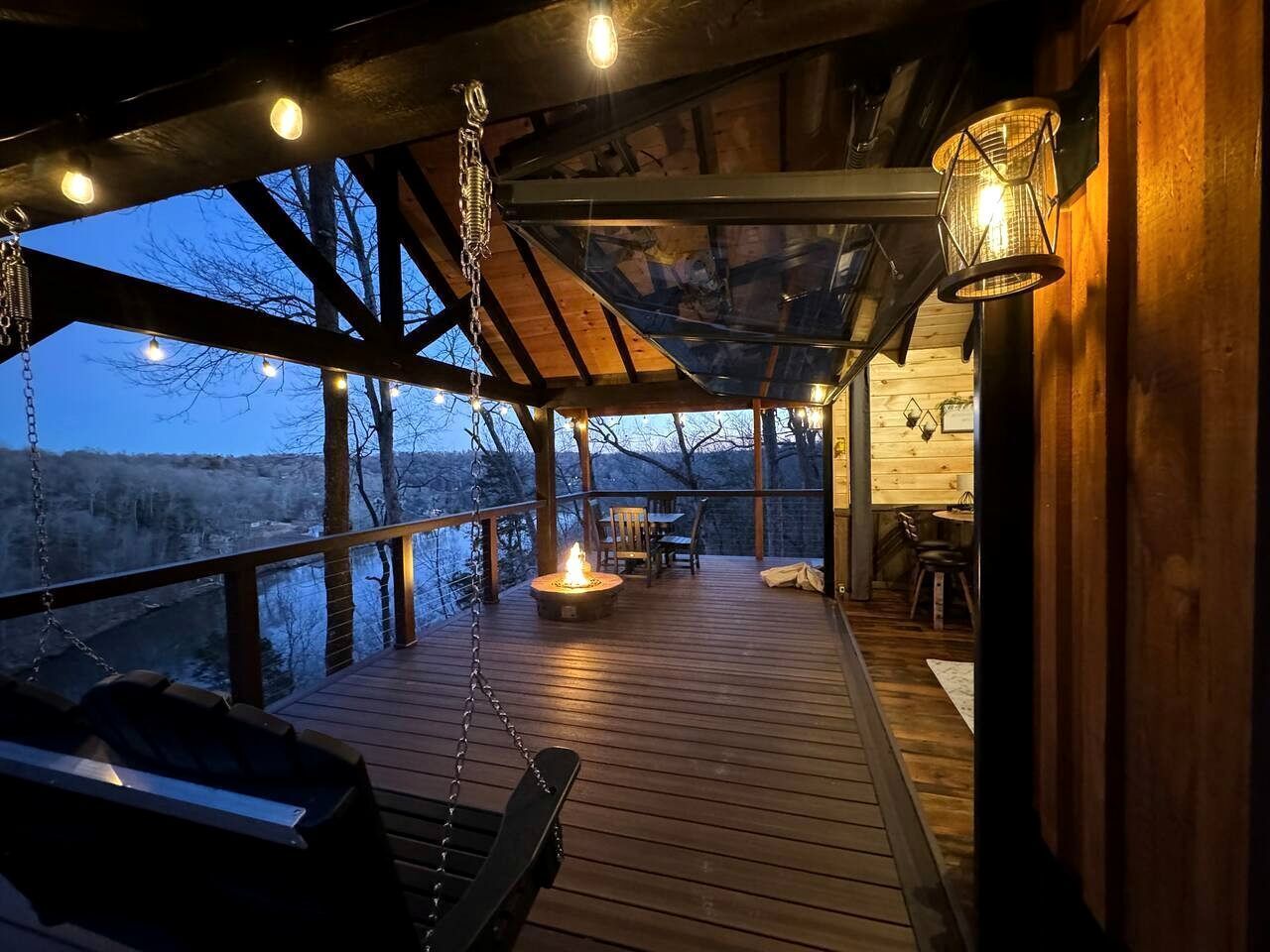A wooden deck with a fire pit, outdoor seating, and a hanging light fixture.