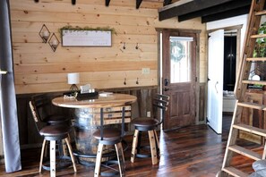 A rustic wooden interior with a round table, four chairs, and a wooden barrel.