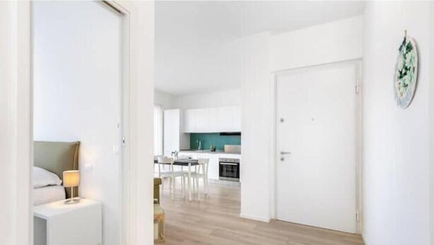 Un apartamento moderno con cocina, comedor y un dormitorio con mesita de noche y lámpara.