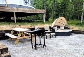 A covered outdoor seating area with a table and chairs, a picnic table, and a circular seating arrangement with a canopy.