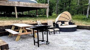 Un área de estar al aire libre techada con mesa y sillas, una mesa de picnic y un espacio de asientos circular con toldo.