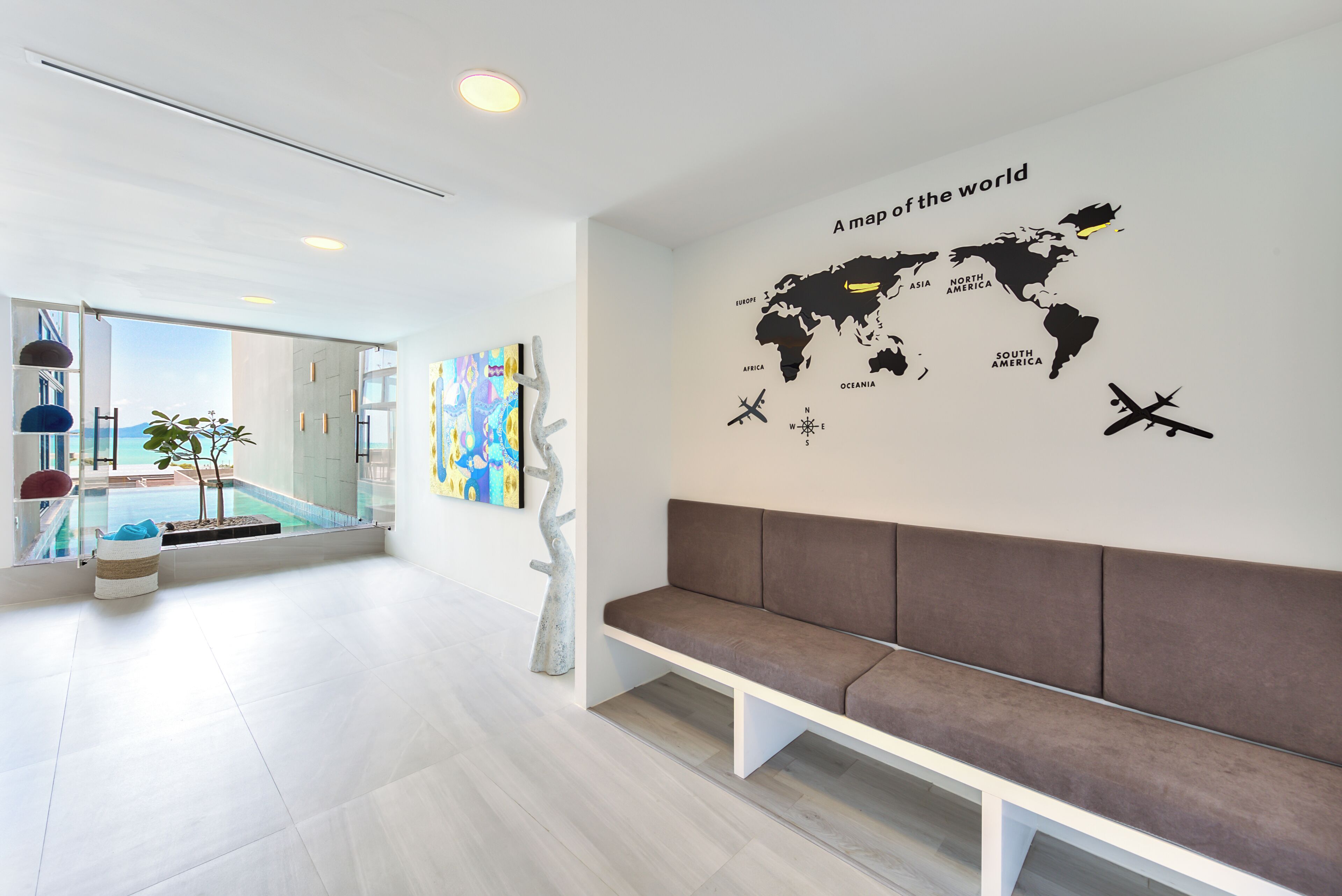 Um interior moderno com arte de parede de mapa-múndi, um banco e vista para uma piscina.