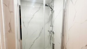 A glass-enclosed shower with a handheld showerhead and a wall-mounted faucet. - Sleek Studio in the Heart of the City (Ghent)