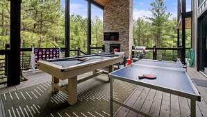 Une terrasse extérieure équipée d’une table de billard, d’une table de ping-pong et d’une cheminée.