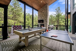 An outdoor deck with a pool table, ping pong table, and a fireplace. - Luxury Cabin with Heated Pool, Sauna & Hot Tub Retreat in Broken Bow, Oklahoma (Broken Bow)