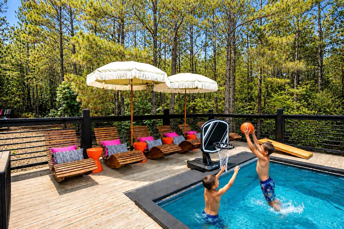 A pool area with wooden deck, lounge chairs, and umbrellas.
