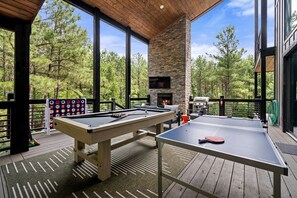 An outdoor deck with a pool table, ping pong table, and a fireplace. - Luxury Cabin with Heated Pool, Sauna & Hot Tub Retreat in Broken Bow, Oklahoma (Broken Bow)
