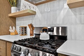 A kitchen with a gas stove, stainless steel appliances, wooden utensils, and a kettle. - Luxury Cabin with Heated Pool, Sauna & Hot Tub Retreat in Broken Bow, Oklahoma (Broken Bow)