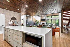 A modern kitchen with a large island, stone wall, and a fireplace. - Luxury Cabin with Heated Pool, Sauna & Hot Tub Retreat in Broken Bow, Oklahoma (Broken Bow)