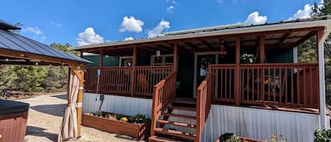 Ein zweigeschossiges Gebäude mit einer Holzterrasse, einer Treppe und einem überdachten Sitzbereich im Freien.