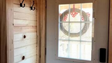 A wooden door with a window, a doorbell, and a wall-mounted hook.