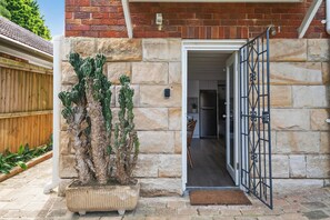 A stone house with a cactus in a pot, a wooden fence, and a metal gate. - Wonderful Waverton with Private Garden (Waverton)