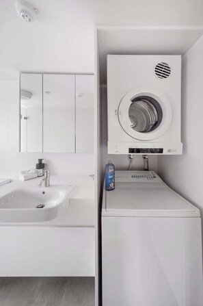 A modern bathroom with a white sink, mirror, and built-in washing machine. - Wonderful Waverton with Private Garden (Waverton)