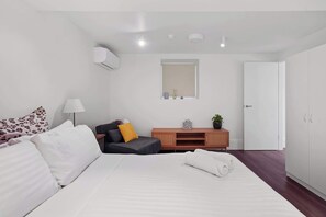 A modern hotel room with a bed, a desk, a chair, a wardrobe, and a small window. - Wonderful Waverton with Private Garden (Waverton)