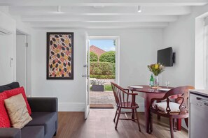 A modern living room with a dining area, a TV mounted on the wall, and a door leading to a garden. - Wonderful Waverton with Private Garden (Waverton)