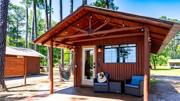A wooden cabin with a porch, a hammock, and a guitar. - Beautiful Cabin by the Lake Nestled in Sabine National Forest for a Romantic Retreat in Hemphill, Texas (Hemphill)