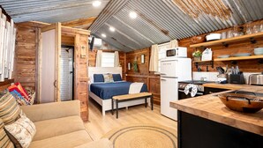 A compact cabin-style room with a bed, kitchenette, and a small seating area. - Beautiful Cabin by the Lake Nestled in Sabine National Forest for a Romantic Retreat in Hemphill, Texas (Hemphill)