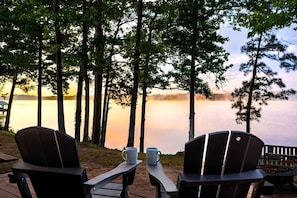 Järvenrantaterassi, jossa on Adirondack-tyyliset tuolit ja pöytä, ja josta avautuu näkymä tyynelle järvelle.