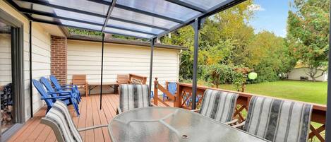 A covered patio with a table and chairs, a brick wall, and a view of the yard.