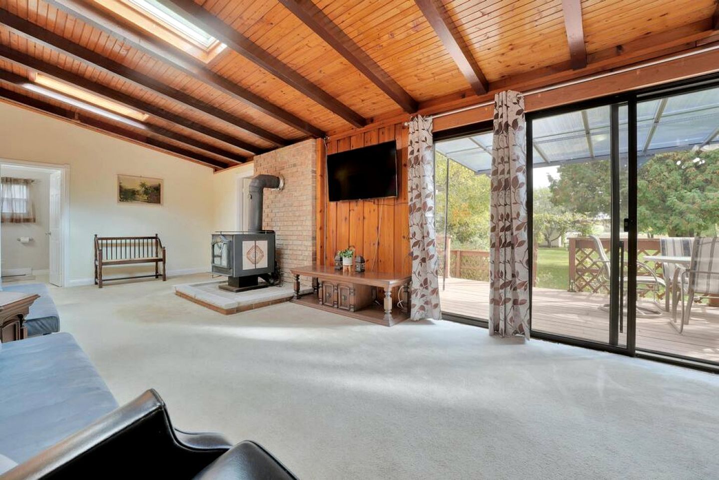 A spacious living area with a fireplace, a television, and a sliding glass door leading to an outdoor deck.
