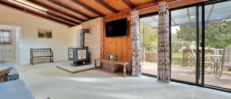 A spacious living area with a fireplace, a television, and a sliding glass door leading to an outdoor deck.