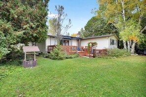 A single-story house with a front porch, a small deck, and a covered patio area. - Rustic Family Cottage with Spectacular Sunset Views on Canal Lake, Near Kawartha Lakes, Ontario (Kirkfield)