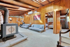 A wooden interior with a fireplace, sofas, and a bed. - Rustic Family Cottage with Spectacular Sunset Views on Canal Lake, Near Kawartha Lakes, Ontario (Kirkfield)