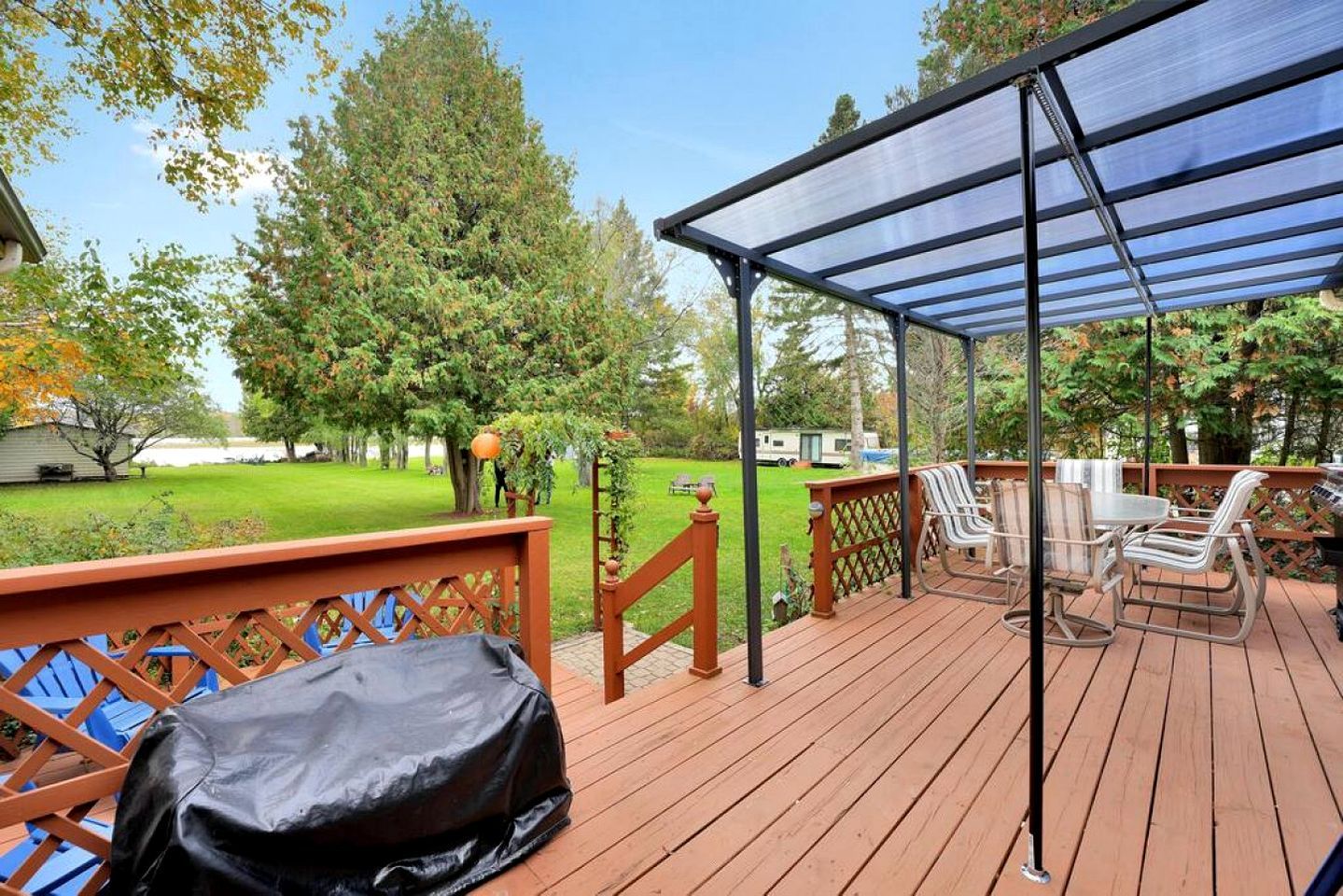 A wooden deck with a covered patio area, outdoor furniture, and a lawn.
