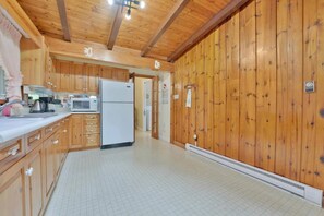 Une cuisine avec des meubles de rangement en bois, un réfrigérateur blanc et un four à micro-ondes.