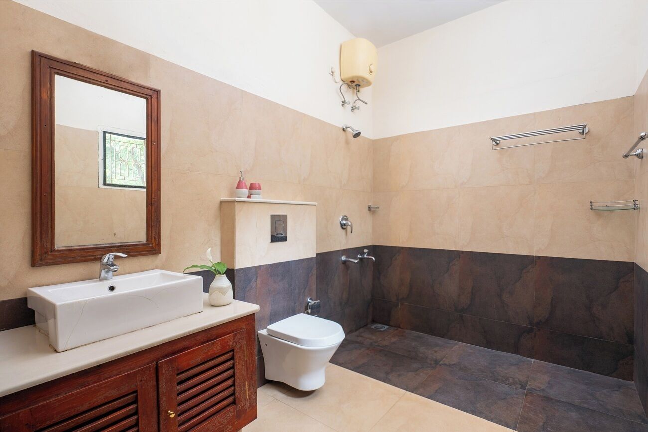 Un baño con lavamanos, espejo, inodoro y zona de ducha.
