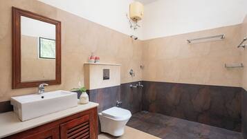 Un baño con lavamanos, espejo, inodoro y zona de ducha.