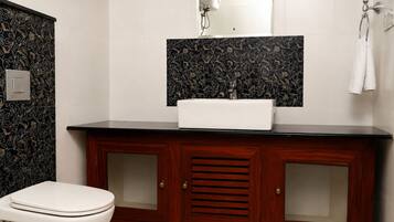 A bathroom with a toilet, a sink with a mirror above it, and a towel rack.