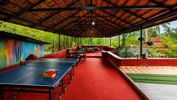 An indoor badminton court with a red carpet, seating area, and a view of greenery outside.
