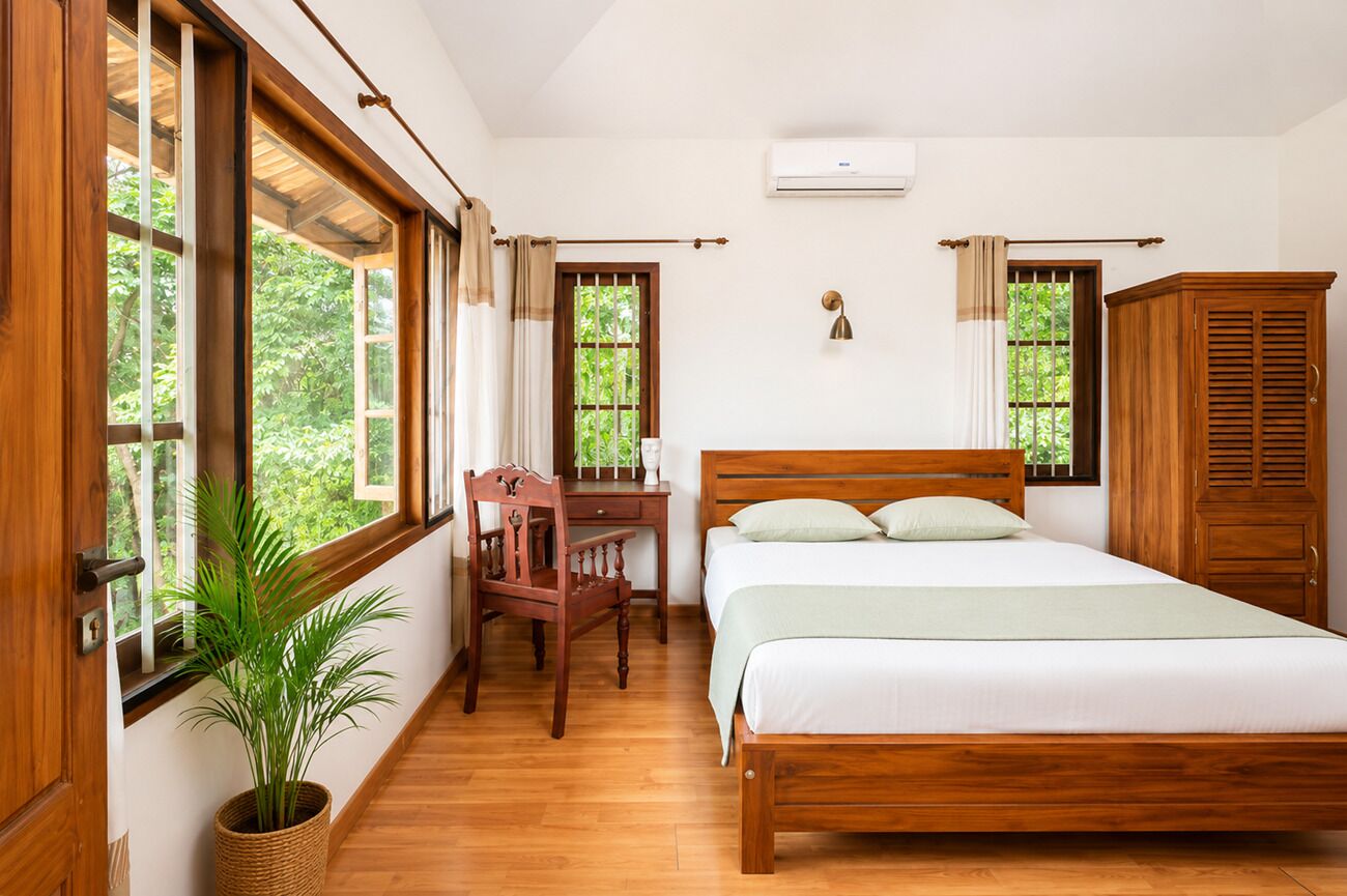 Un dormitorio con una cama de madera, un escritorio, una silla y una planta en maceta.