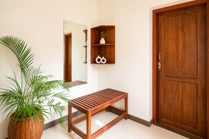 Un banco de madera, una planta en maceta, una puerta de madera y una estantería con adornos.
