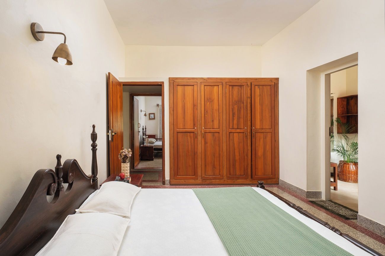 Un dormitorio con cama, armario de madera y una lámpara fijada a la pared.