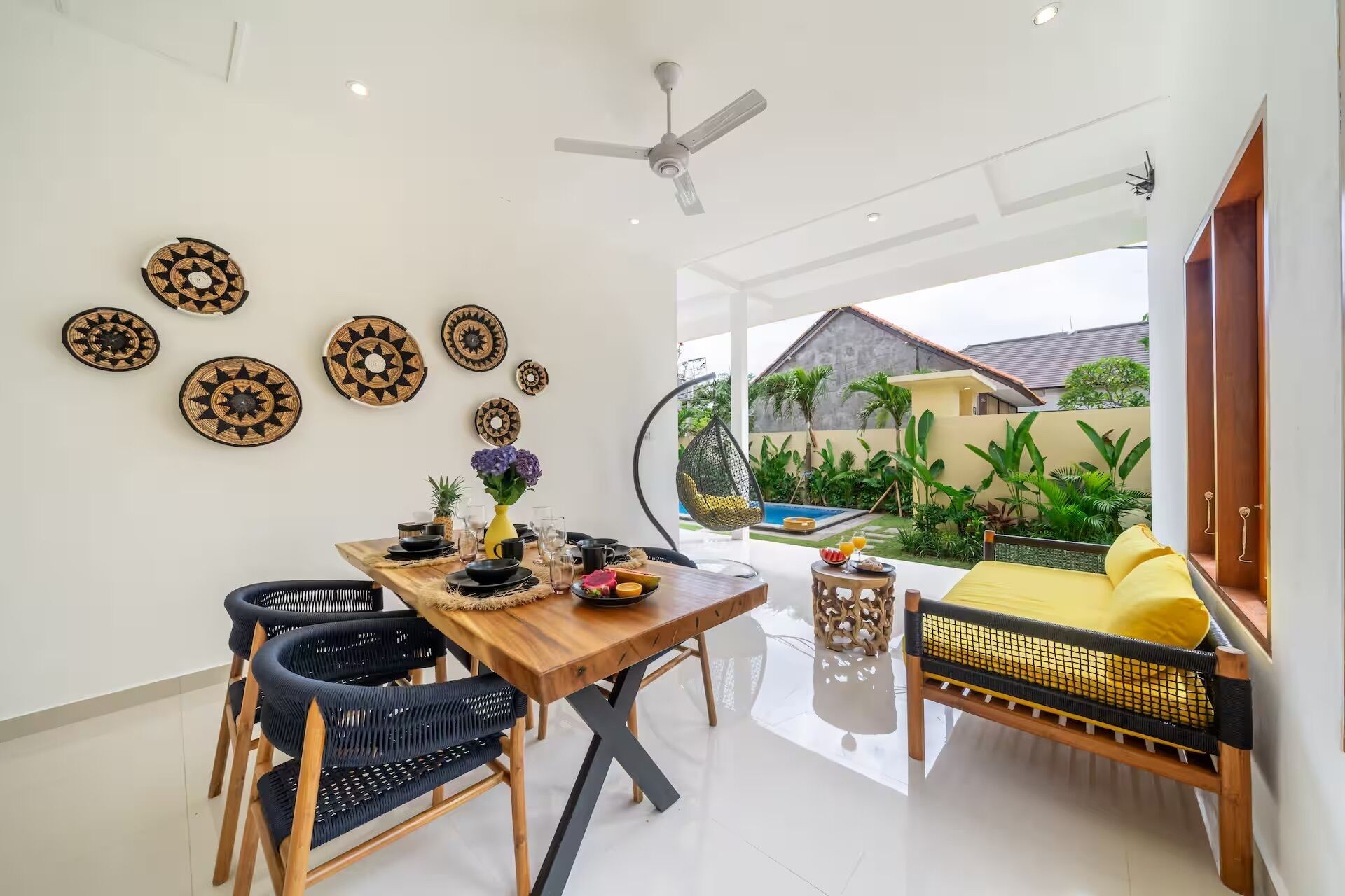 A dining area with a wooden table, black woven chairs, and decorative plates on the wall.
