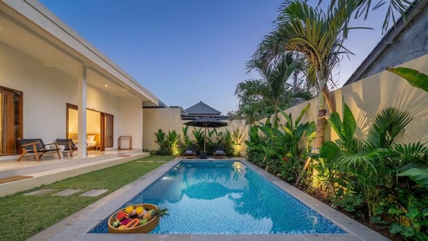 A modern pool with a lounge area, a covered seating area, and lush tropical plants. - Lasterra Villa (Kerobokan)