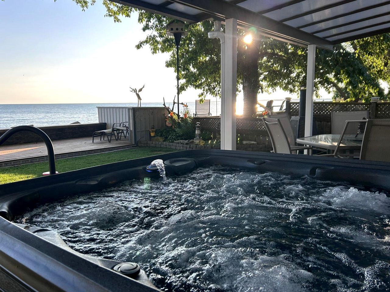Een hottub met uitzicht op zee, buitenzitplaatsen en een pergola.