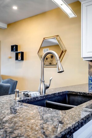 A kitchen with a granite countertop, stainless steel faucet, and a gold-colored hexagonal mirror. - Lakeside Vacation Rental on Lake Erie for a Unique Escape in Leamington, Ontario (Leamington)