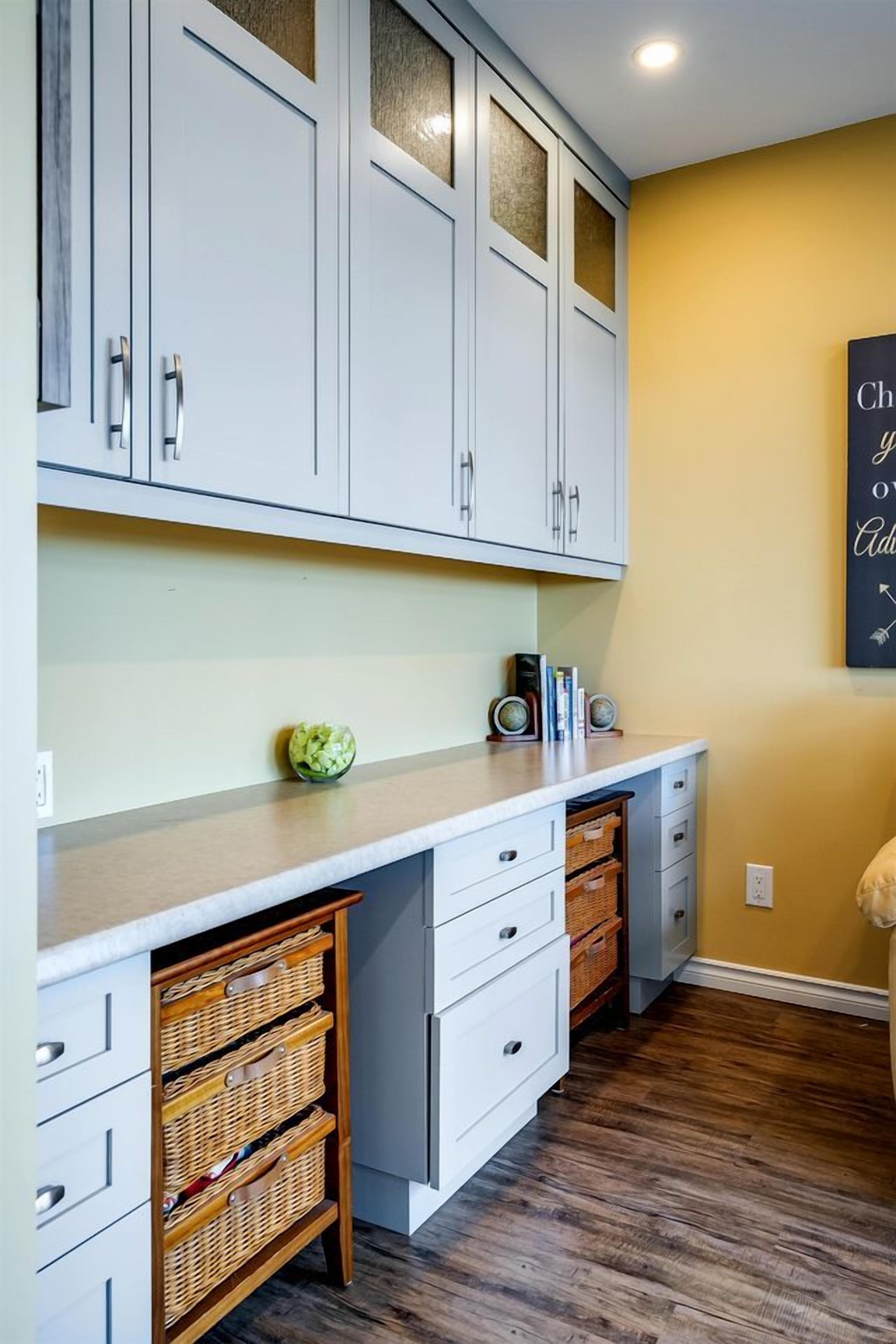 A kitchen with white cabinets, a wooden countertop, wicker baskets, and a wall clock.