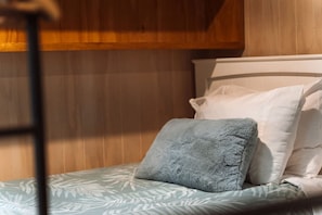 A bunk bed with a blue pillow and a patterned bedspread.