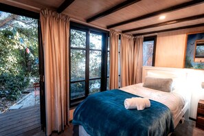Ein Schlafzimmer mit großem Fenster, einem Bett mit blauer Decke und einem Kopfteil.