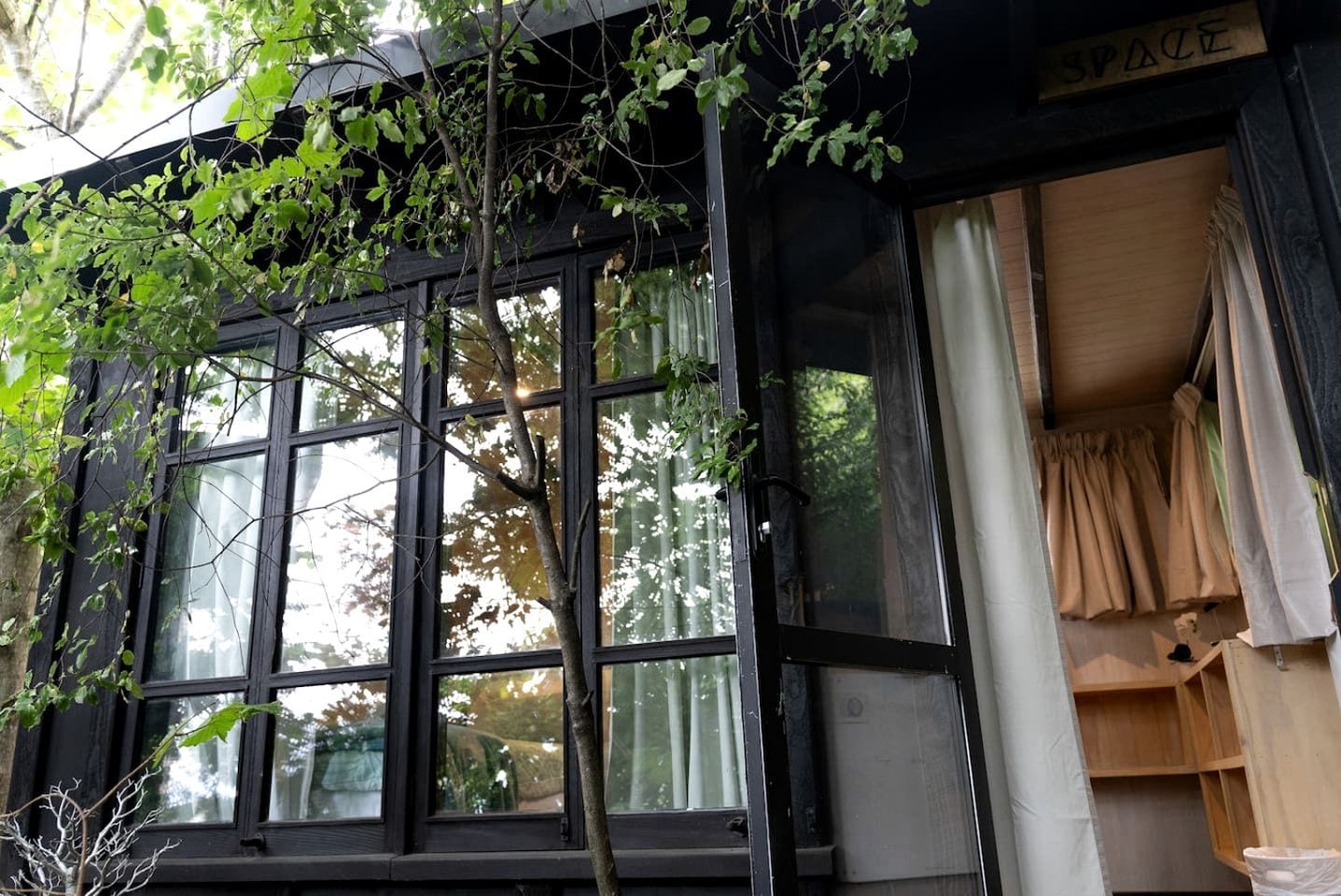 A building with large windows, a tree in front, and a sign that reads 'SPACE'.